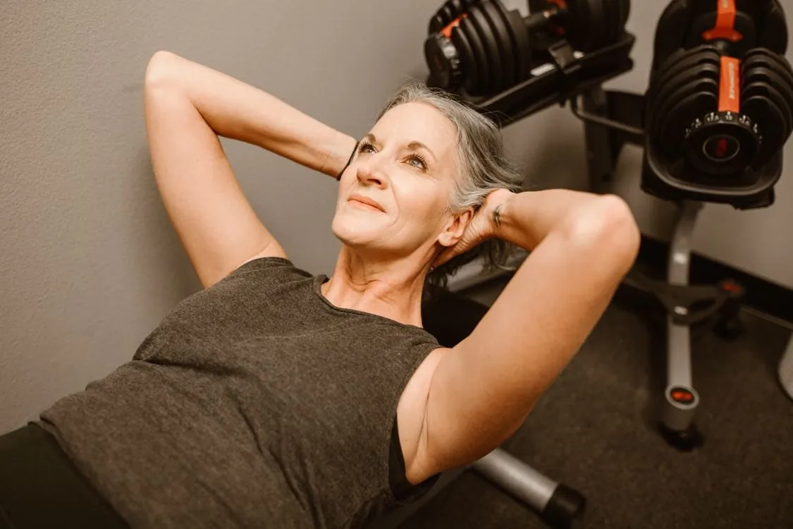 An older adult performing an abdominal exercise in a gym.