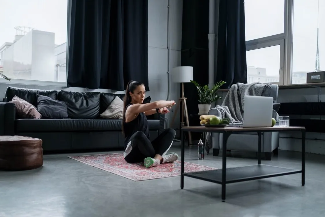 An adult stretching on a mat in a living room.