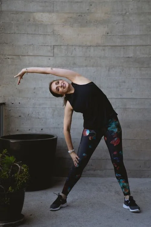 An adult performing a standing side stretch indoors.